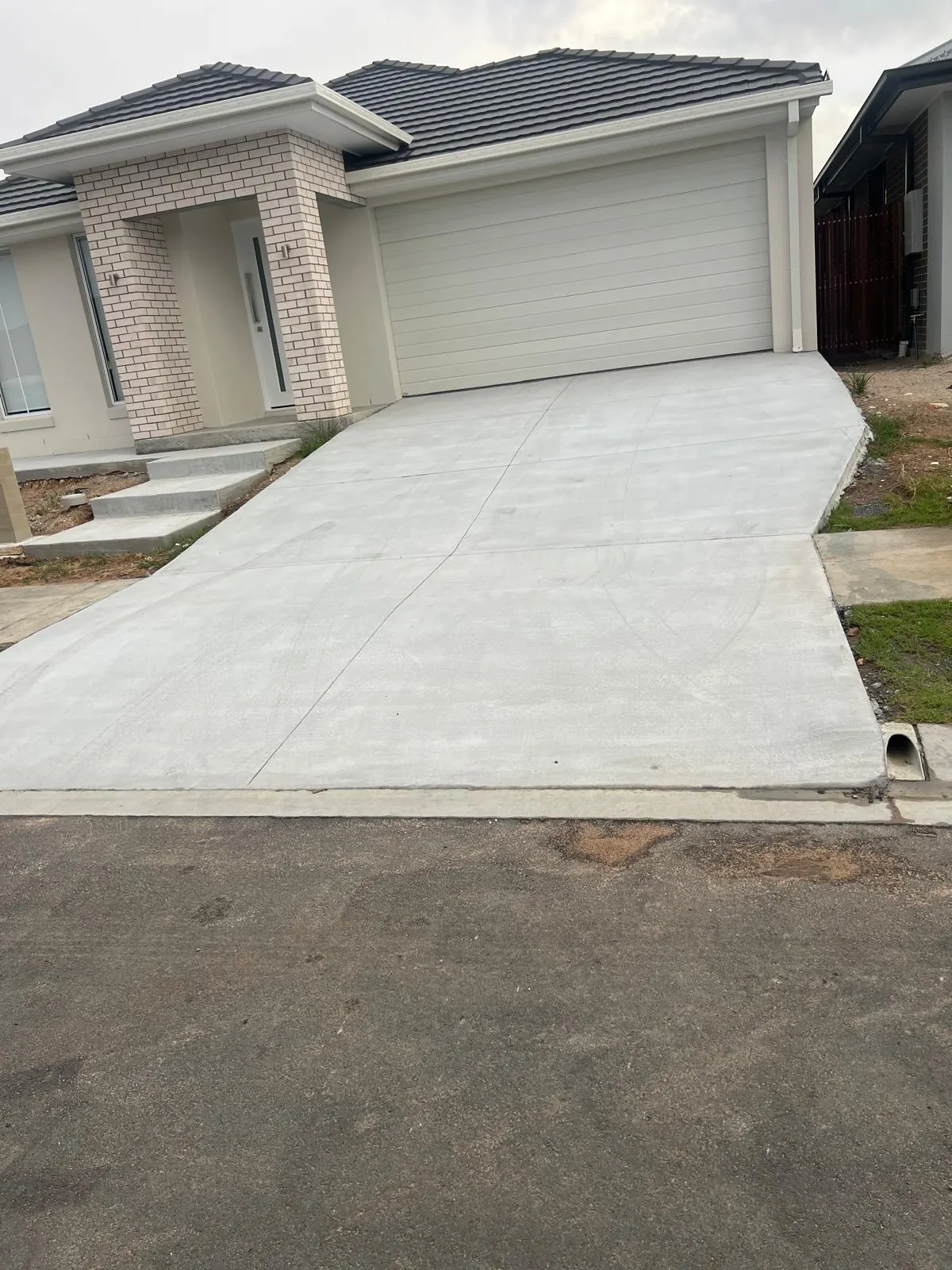 Smooth plain concrete driveway with control joints in front of a Brisbane home